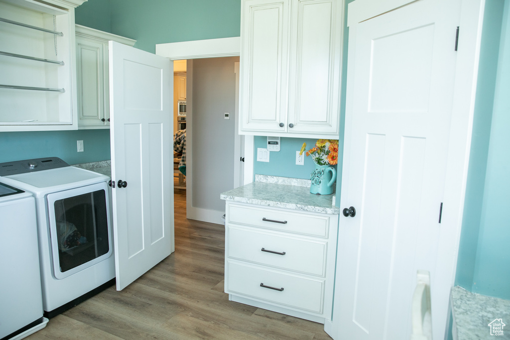 Laundry room featuring washer and clothes dryer, cabinets, and wood-type flooring