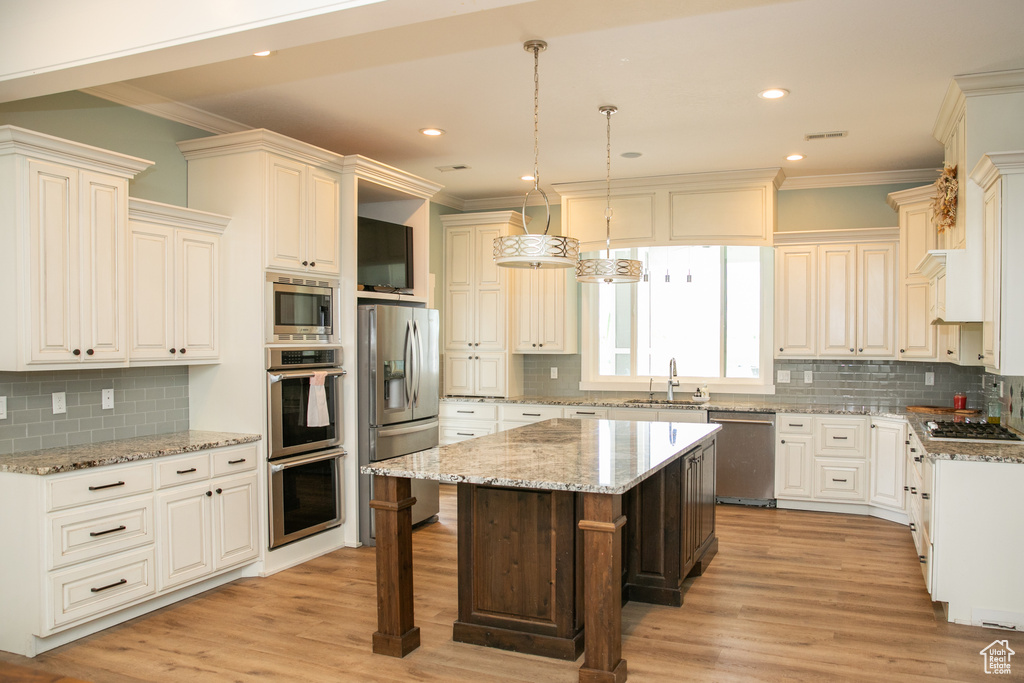 Kitchen with a kitchen island, decorative backsplash, stainless steel appliances, and light hardwood / wood-style floors