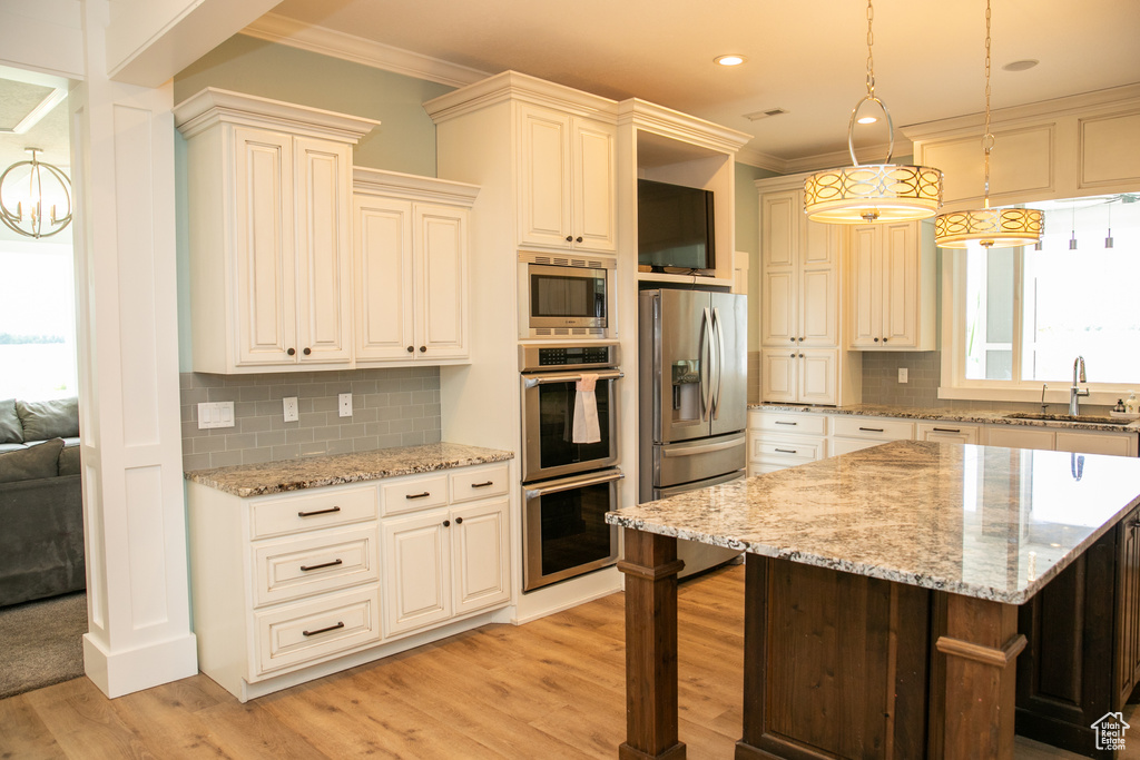 Kitchen with sink, appliances with stainless steel finishes, light hardwood / wood-style flooring, and backsplash