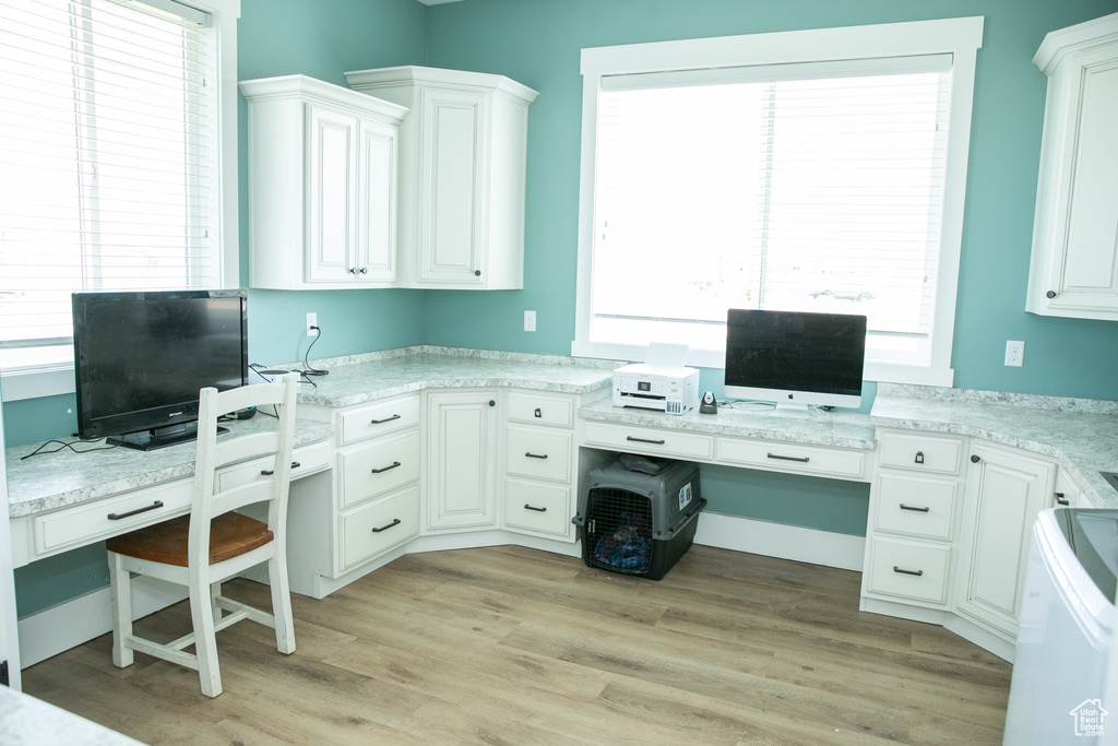 Office space with light hardwood / wood-style flooring and built in desk