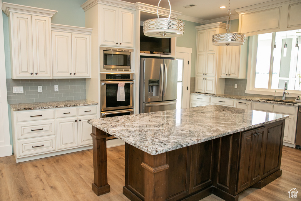 Kitchen featuring sink, decorative backsplash, stainless steel appliances, and a kitchen island