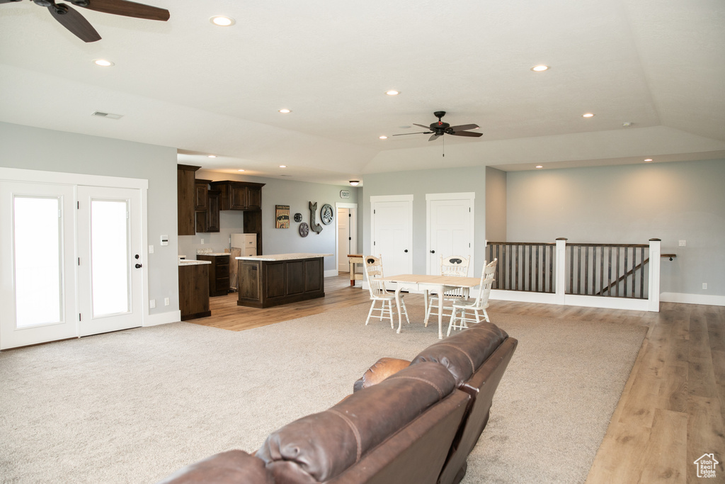 Living room with lofted ceiling, ceiling fan, and light wood-type flooring