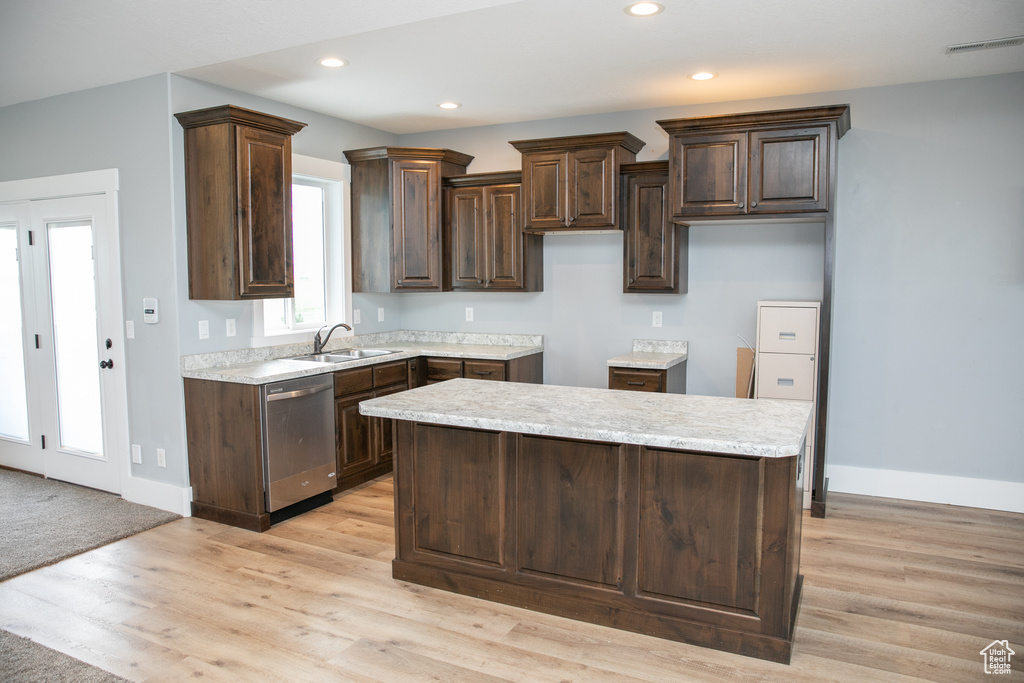 Kitchen with dark brown cabinets, dishwasher, light hardwood / wood-style floors, and a center island