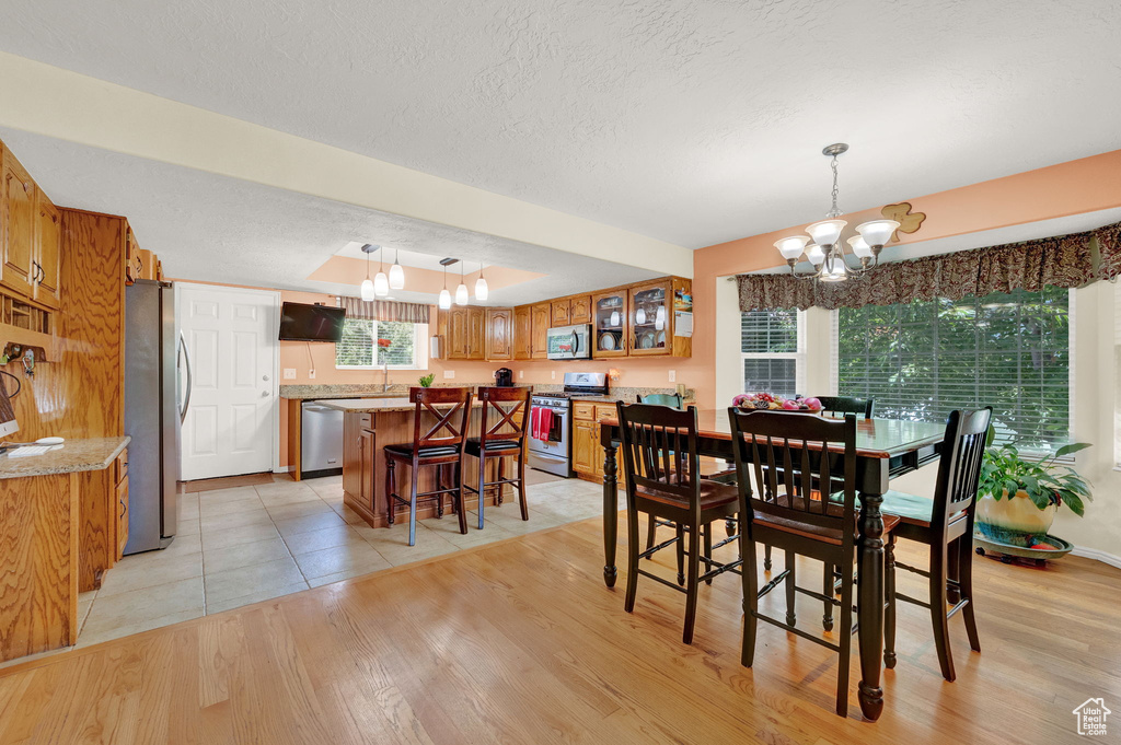 Dining room with light hardwood / wood-style flooring, an inviting chandelier, and a textured ceiling