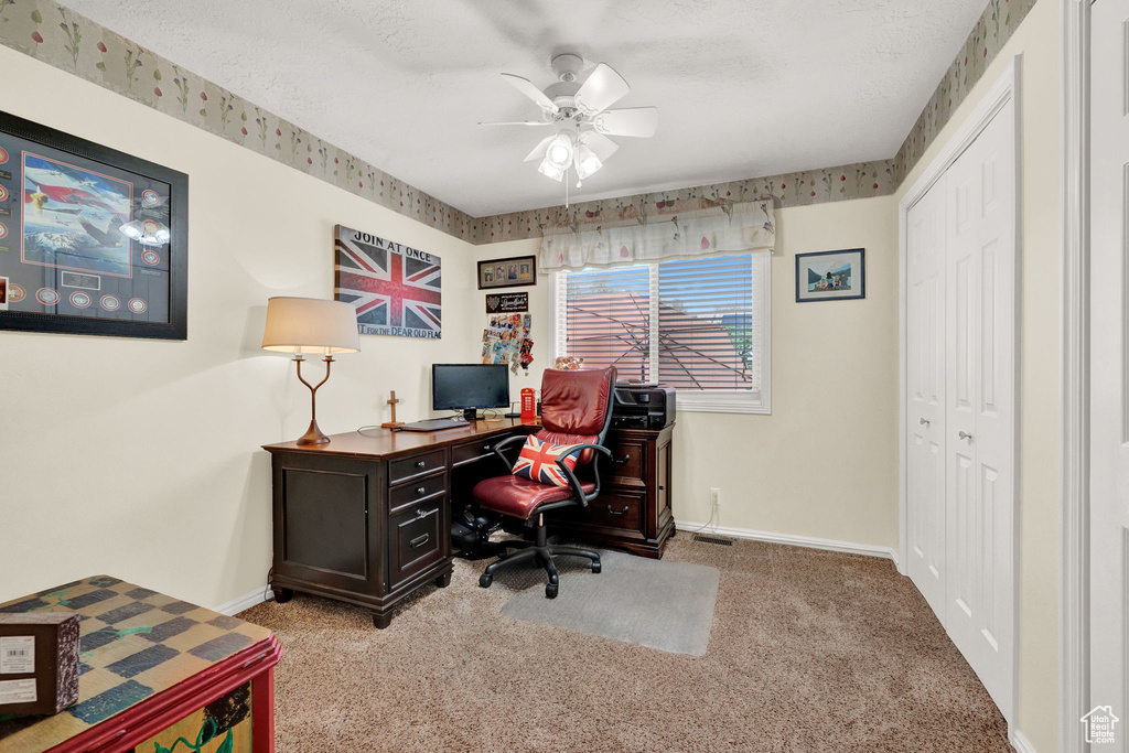 Carpeted office space featuring ceiling fan