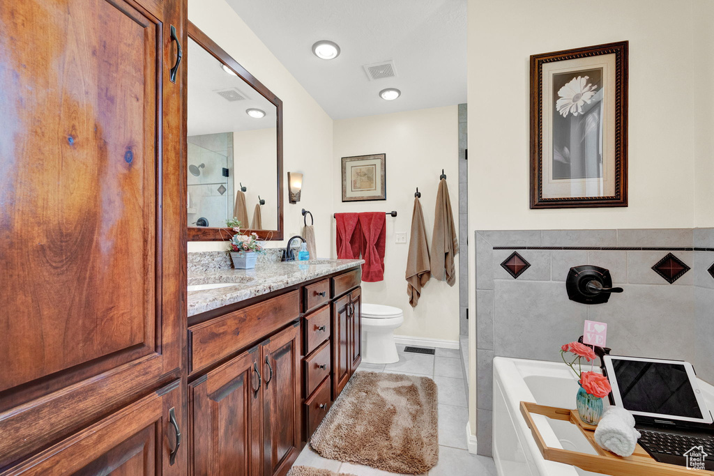 Bathroom with vanity, toilet, tile patterned floors, and a washtub