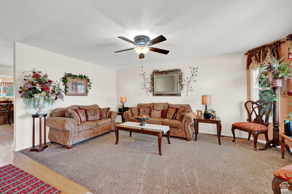 Living room with a wealth of natural light, wood-type flooring, and ceiling fan