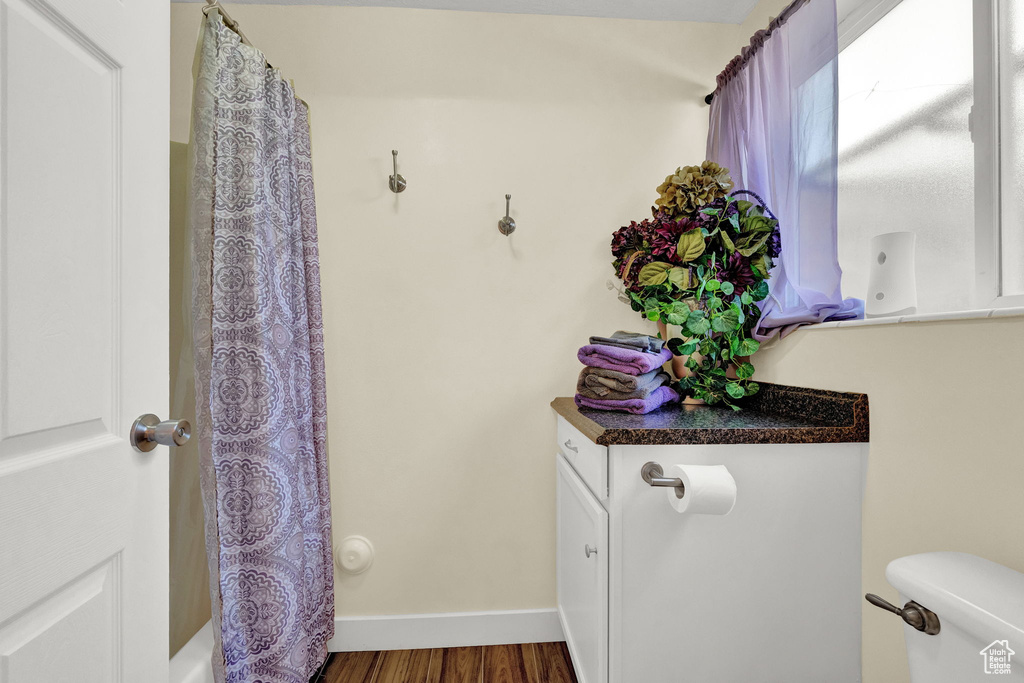 Full bathroom featuring hardwood / wood-style floors, toilet, vanity, and shower / tub combo with curtain