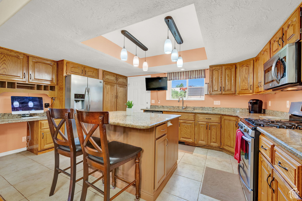 Kitchen with a kitchen island, a textured ceiling, a tray ceiling, and stainless steel appliances