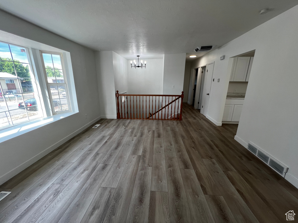 Unfurnished room with hardwood / wood-style flooring and a notable chandelier