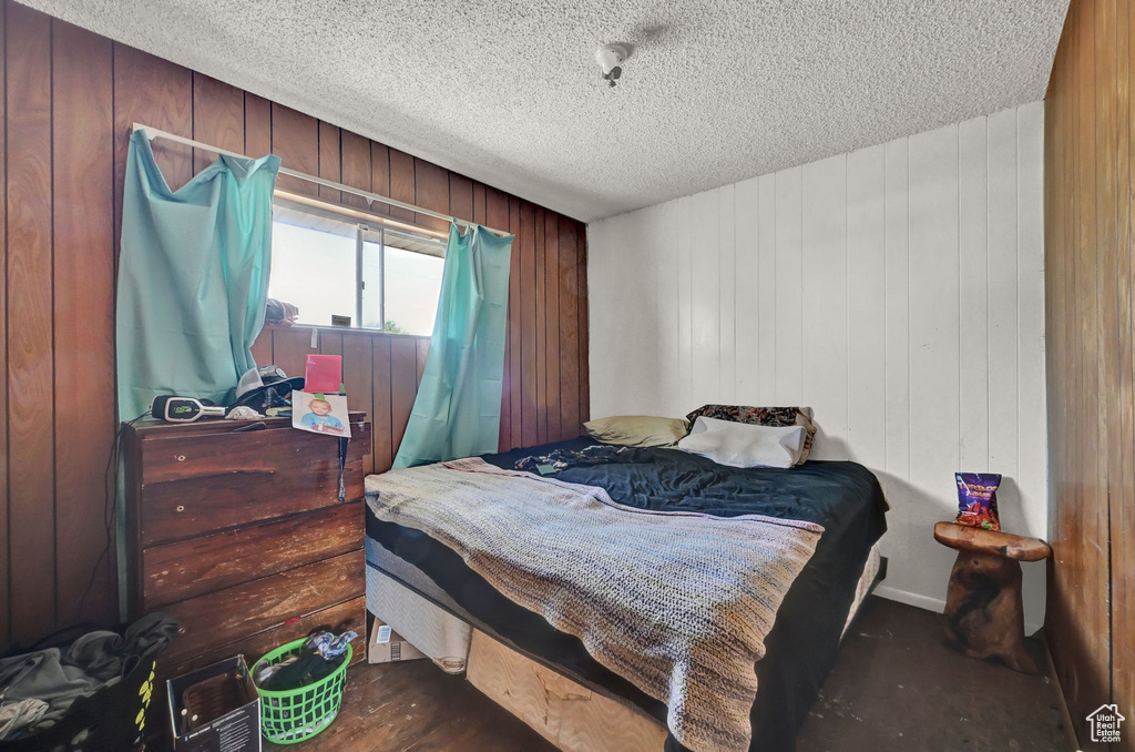 Bedroom featuring a textured ceiling and wooden walls