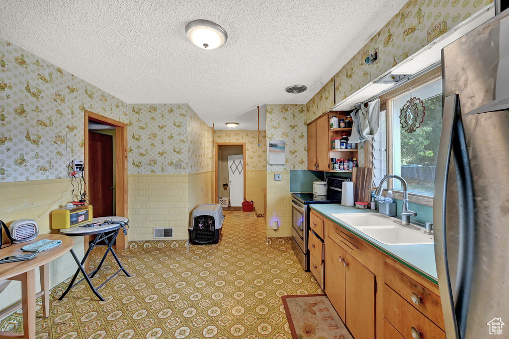 Kitchen with sink, light tile patterned flooring, a textured ceiling, and appliances with stainless steel finishes