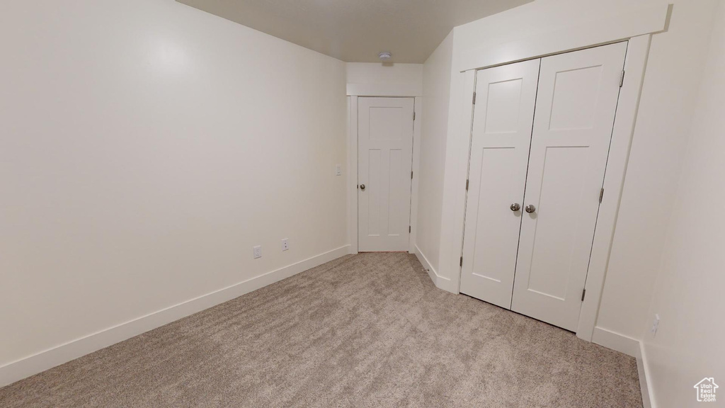 Unfurnished bedroom featuring light carpet and a closet