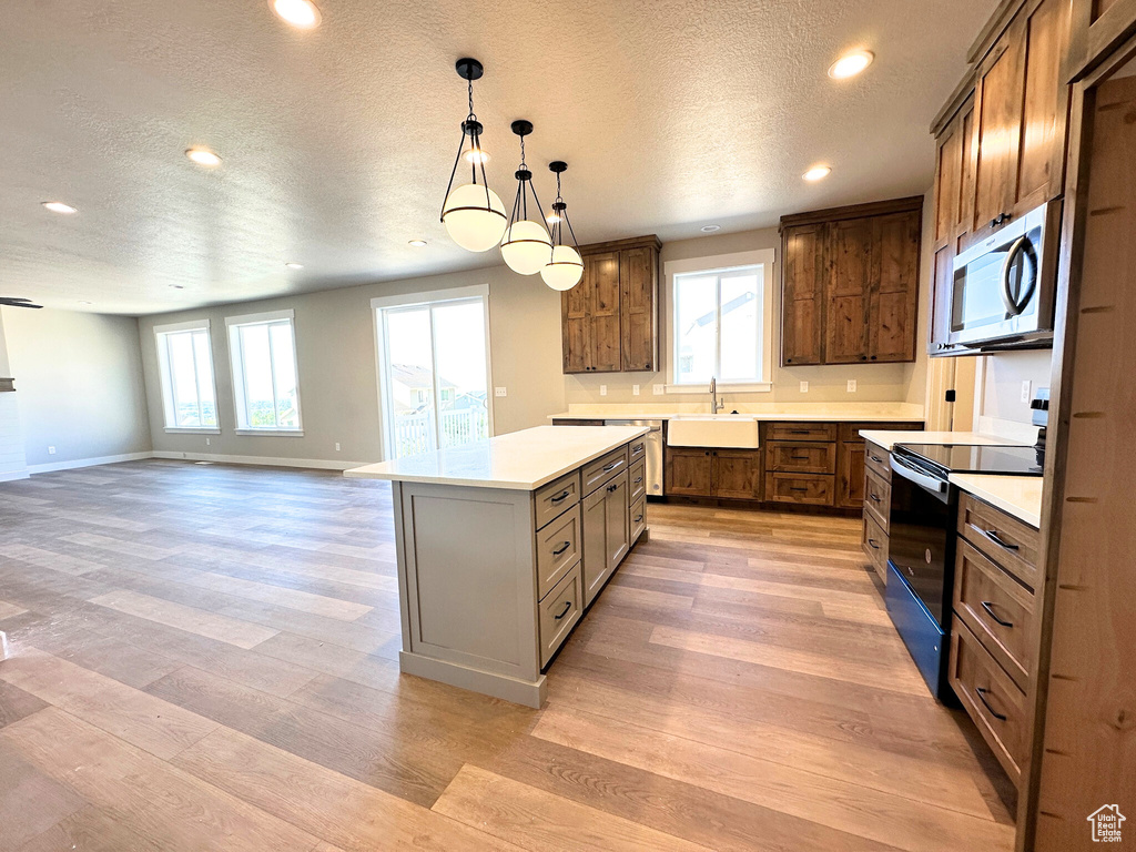 Kitchen featuring black range with electric cooktop, a wealth of natural light, a kitchen island, and light hardwood / wood-style floors