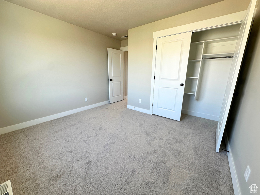 Unfurnished bedroom with a closet and light carpet