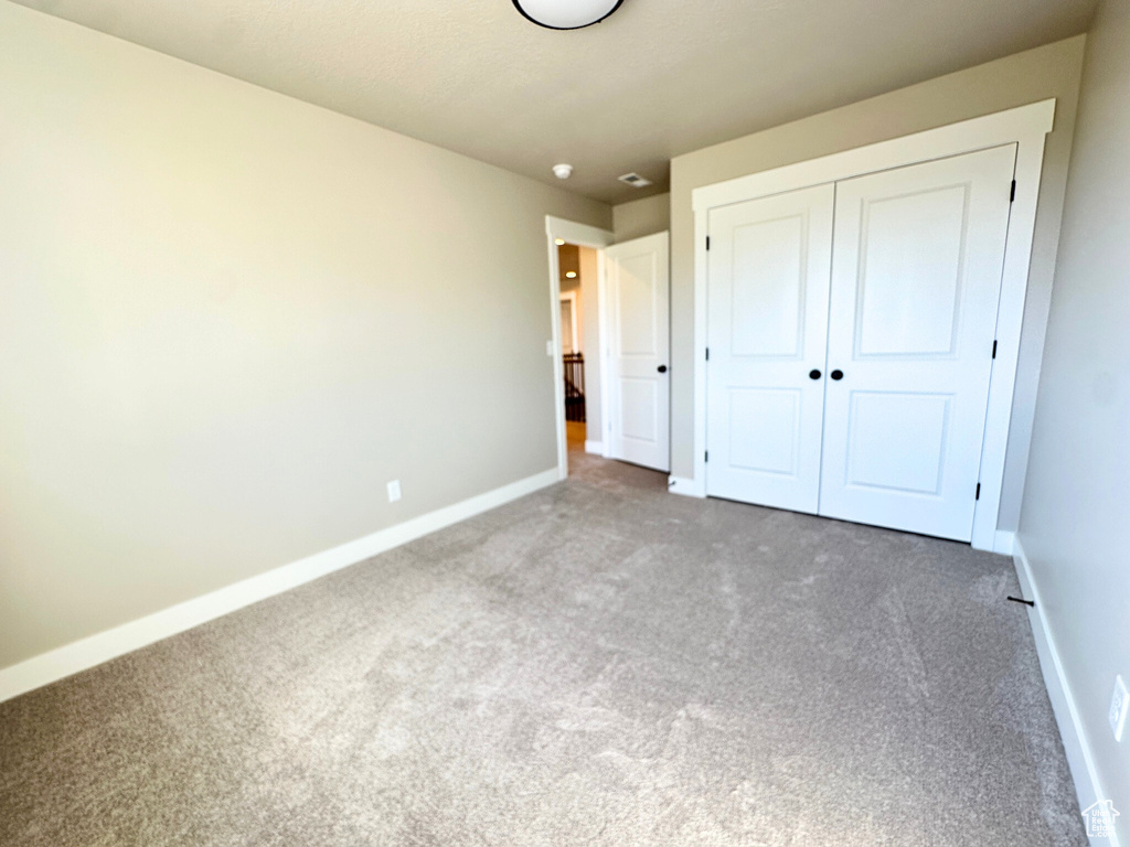 Unfurnished bedroom with a closet and carpet floors