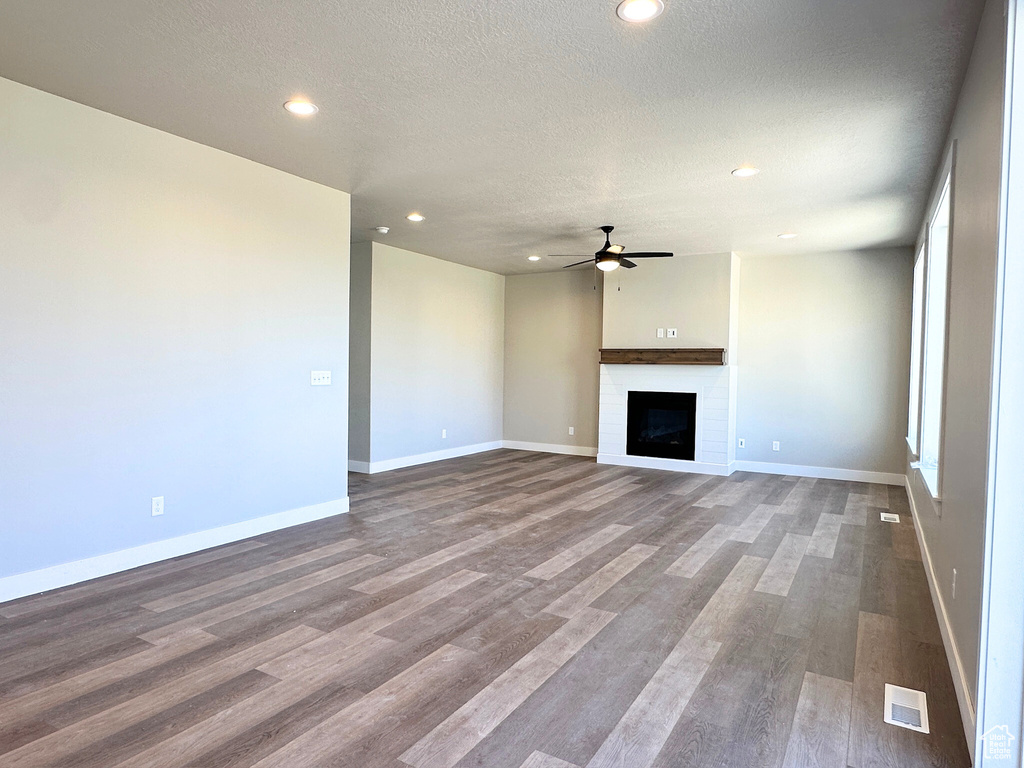 Unfurnished living room featuring a textured ceiling, hardwood / wood-style flooring, and ceiling fan