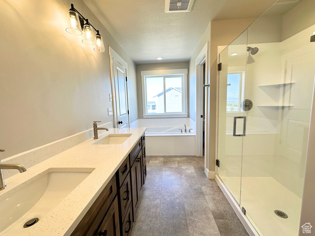 Bathroom featuring separate shower and tub, a textured ceiling, and vanity