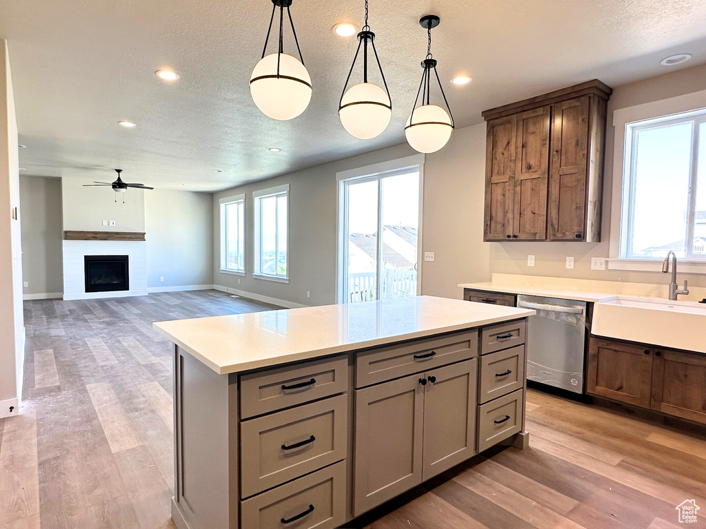 Kitchen featuring decorative light fixtures, dishwasher, a center island, and a healthy amount of sunlight