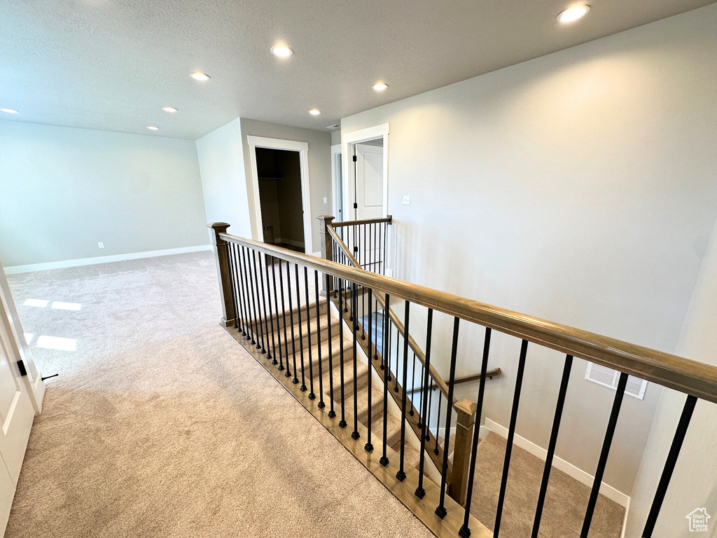 Corridor featuring light carpet and a textured ceiling