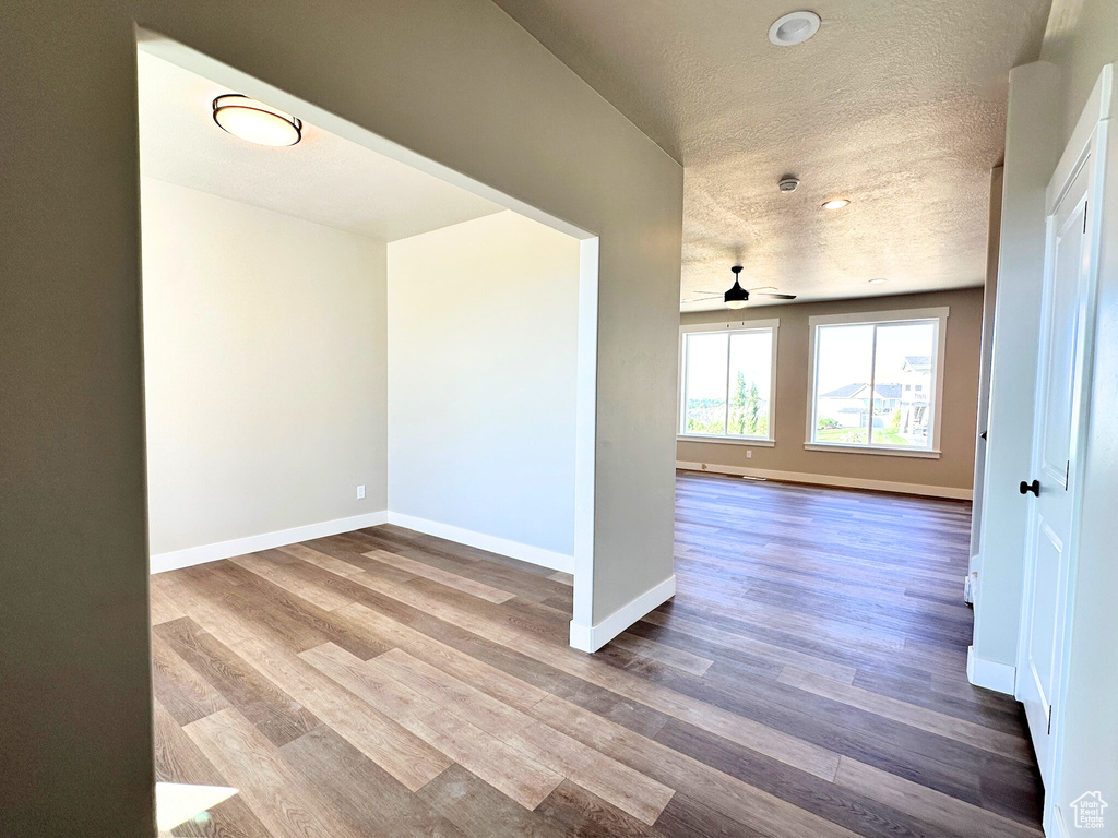 Empty room featuring a textured ceiling, ceiling fan, and wood-type flooring