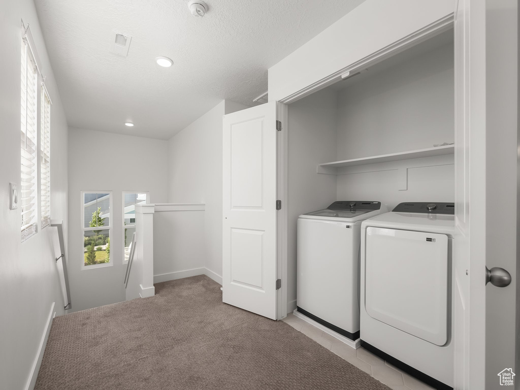 Washroom with light carpet and washer and clothes dryer