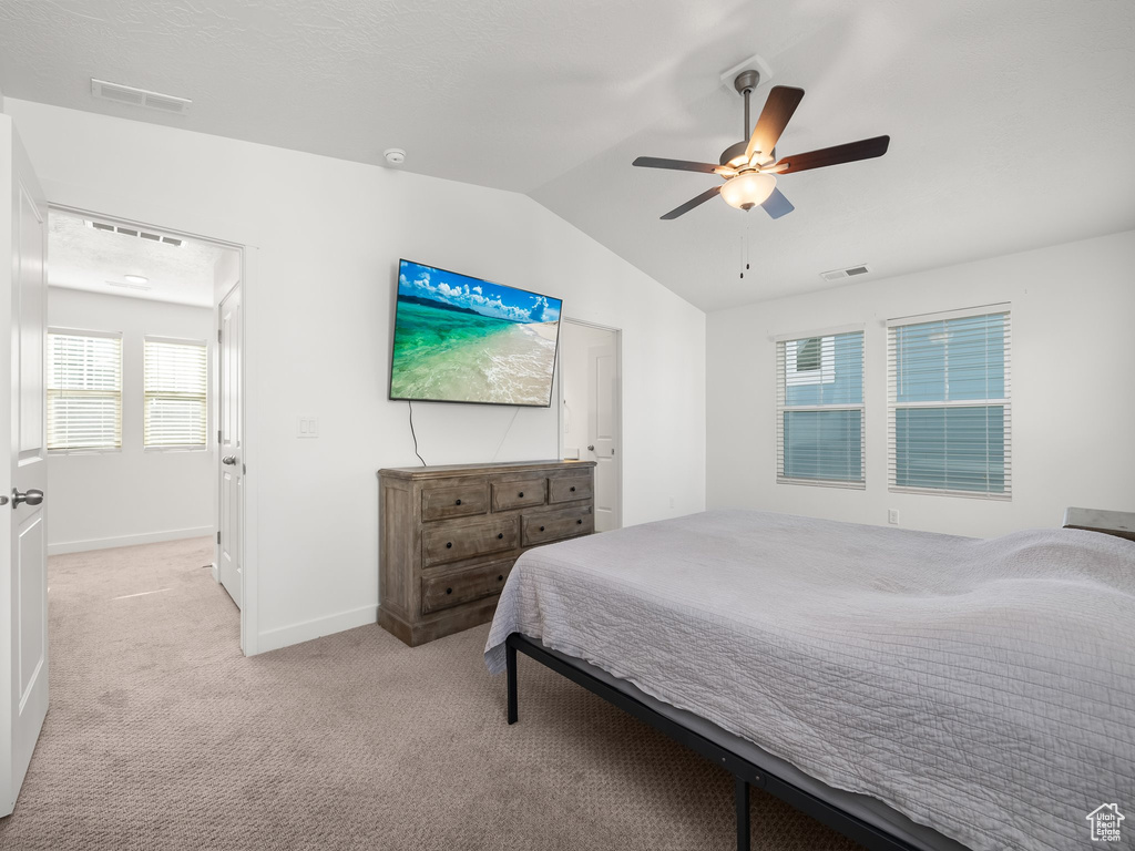 Carpeted bedroom featuring vaulted ceiling and ceiling fan