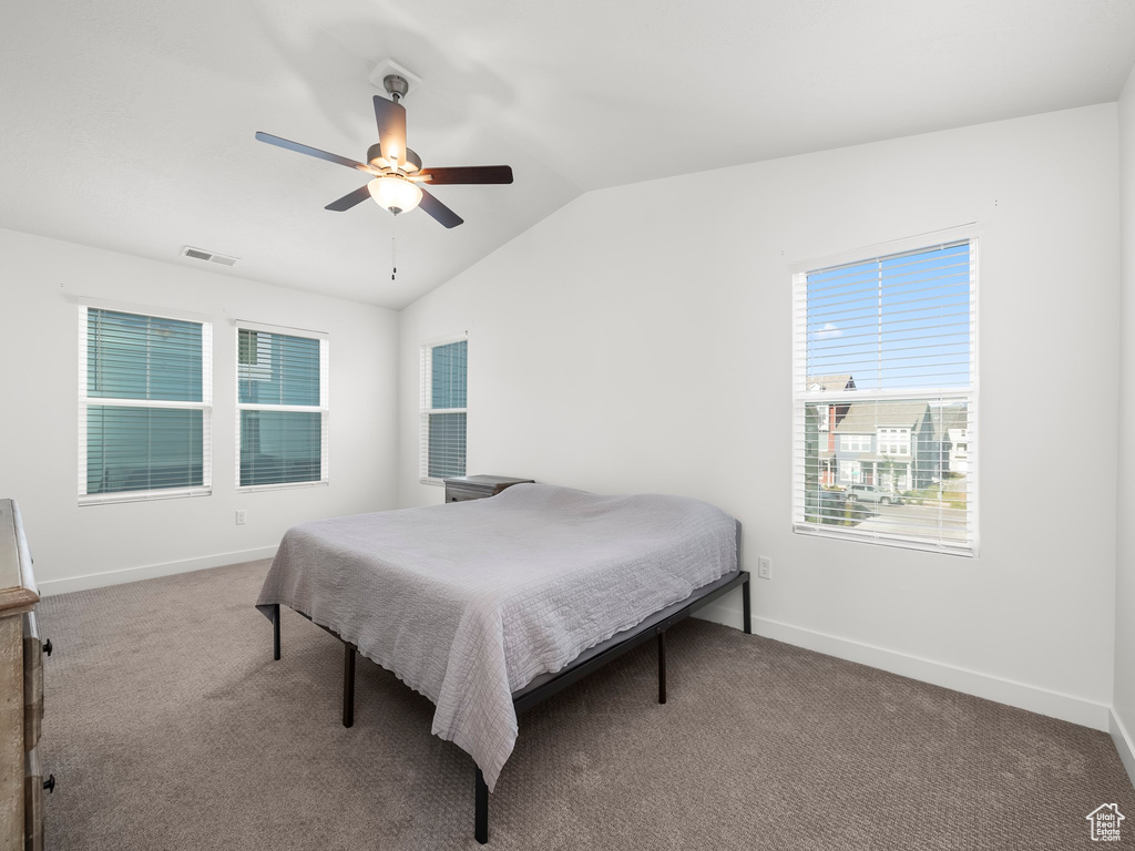 Carpeted bedroom featuring ceiling fan and vaulted ceiling