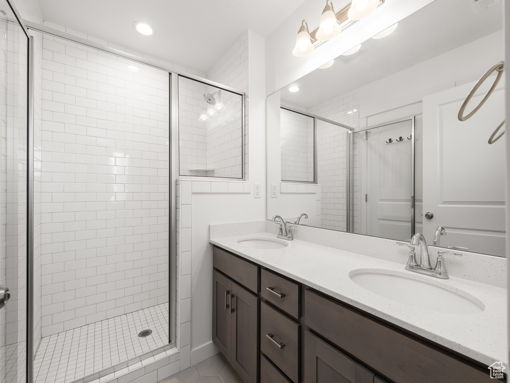 Bathroom featuring an enclosed shower, tile patterned flooring, and dual bowl vanity