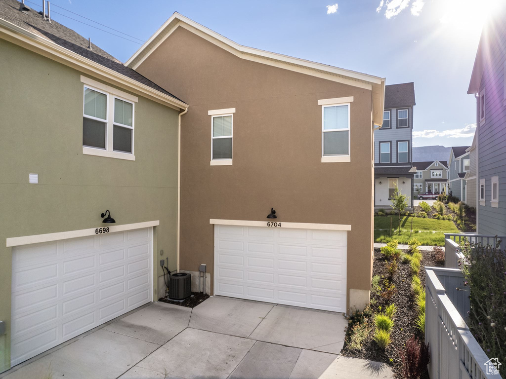 View of property exterior featuring a garage and cooling unit