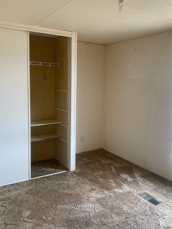 Unfurnished bedroom with a textured ceiling, carpet, and a closet