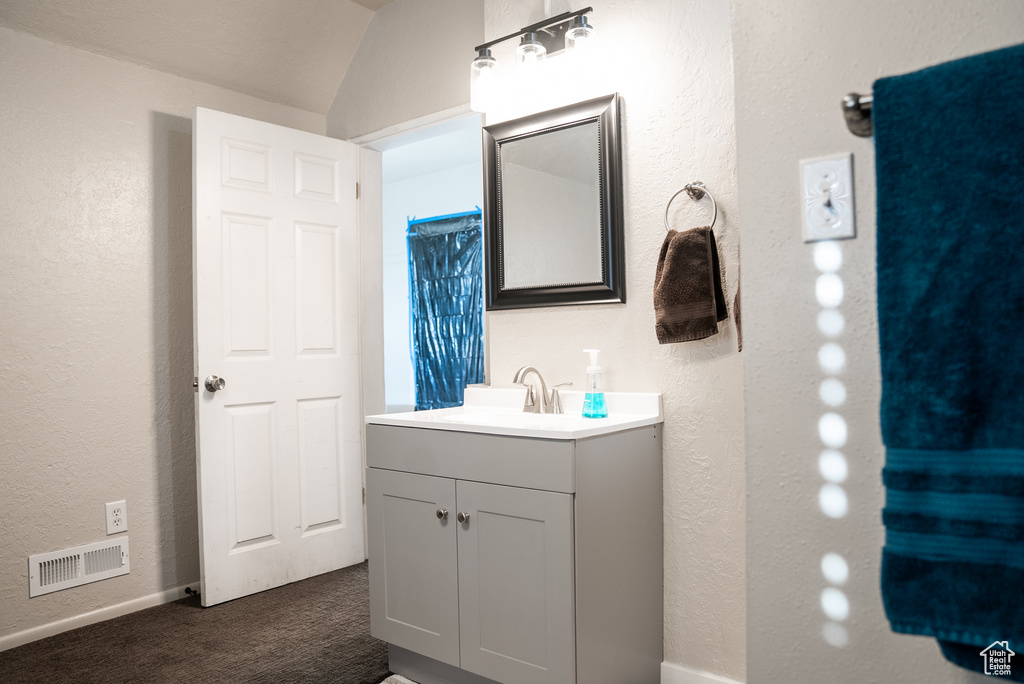 Bathroom featuring lofted ceiling and vanity