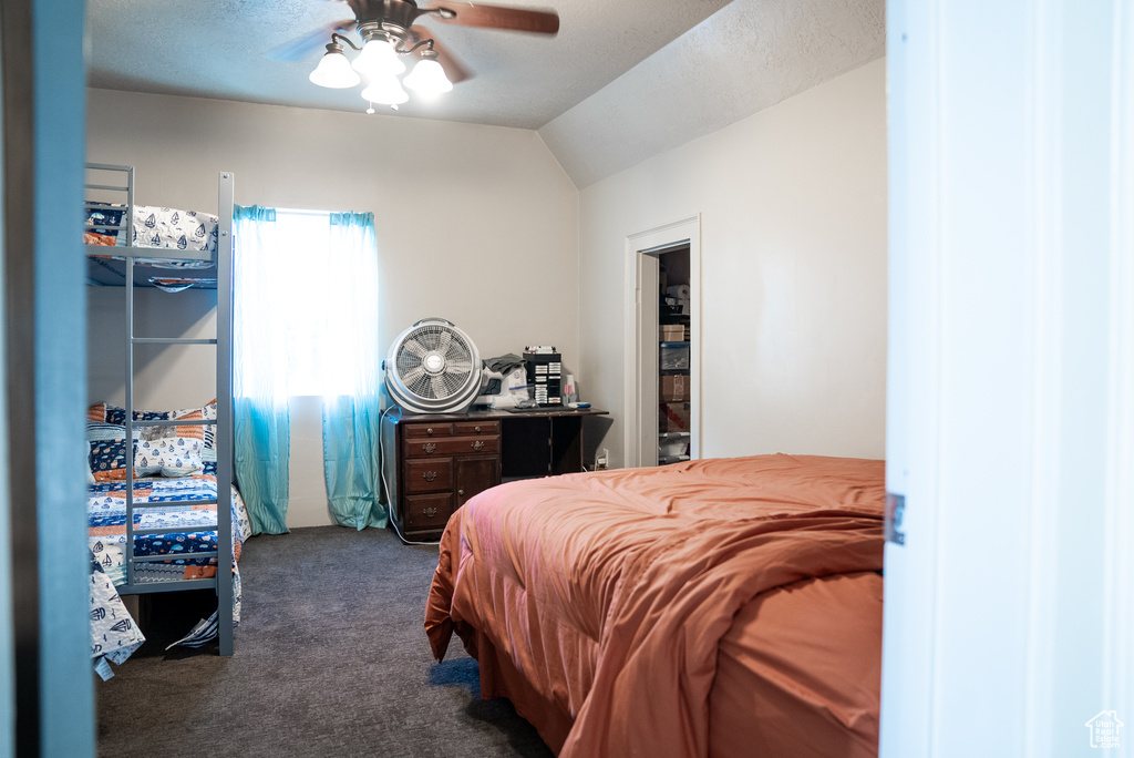 Bedroom with lofted ceiling, dark carpet, and ceiling fan