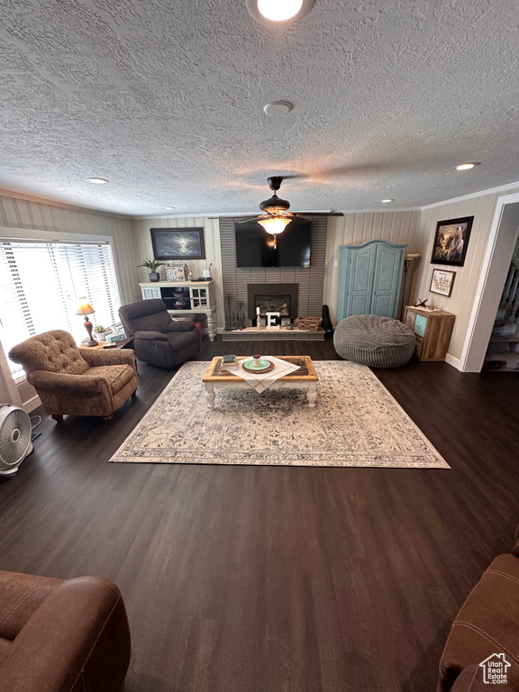 Living room featuring a textured ceiling, a large fireplace, and dark hardwood / wood-style flooring