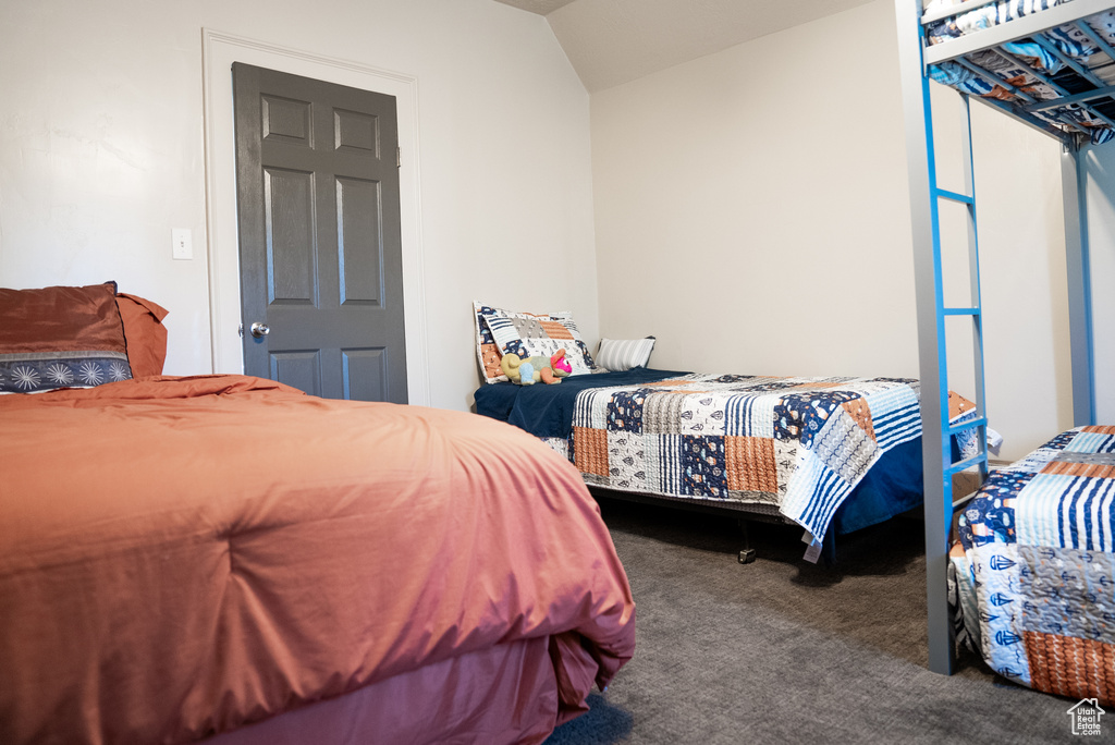 Bedroom featuring dark carpet and lofted ceiling