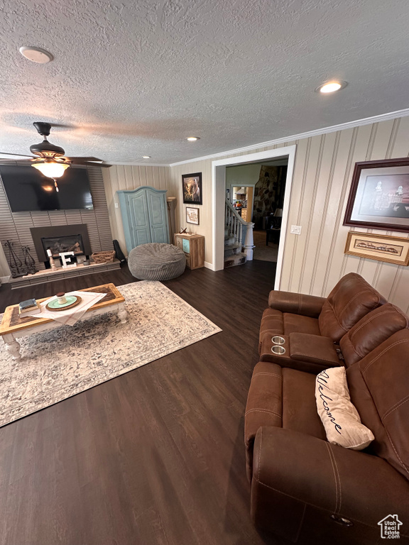 Living room with ceiling fan, a fireplace, a textured ceiling, and dark hardwood / wood-style floors