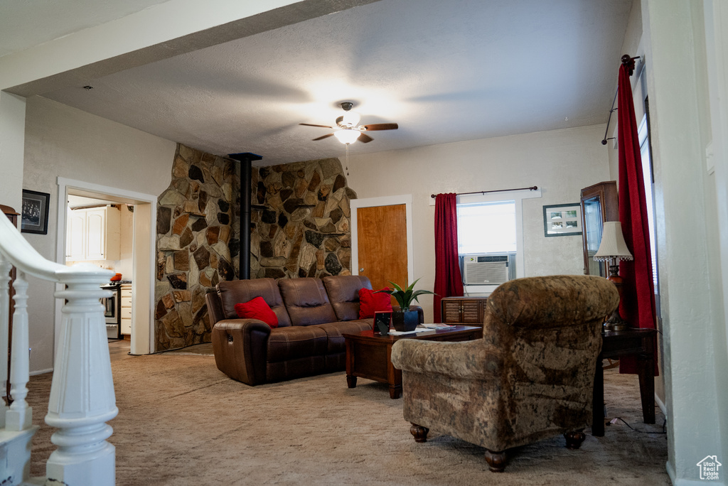 Living room with a wood stove, carpet floors, ceiling fan, and cooling unit