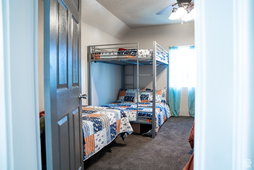 Bedroom with a textured ceiling, carpet floors, and ceiling fan