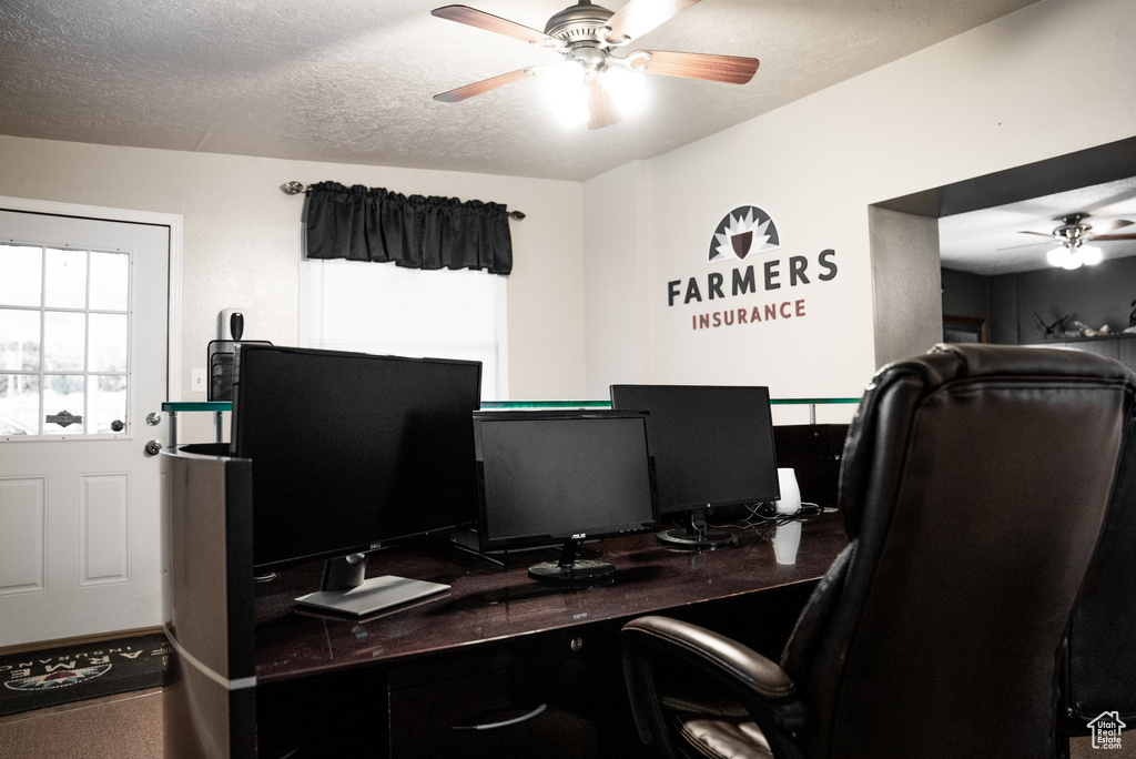 Carpeted office featuring a textured ceiling and ceiling fan