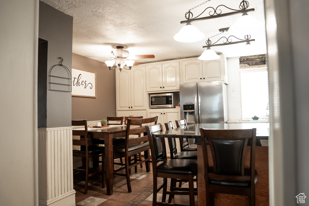 Kitchen with a textured ceiling, white cabinets, ceiling fan, stainless steel appliances, and tile patterned floors