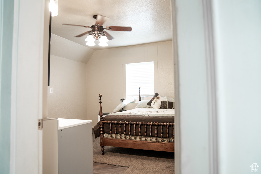 Carpeted bedroom with ceiling fan and vaulted ceiling