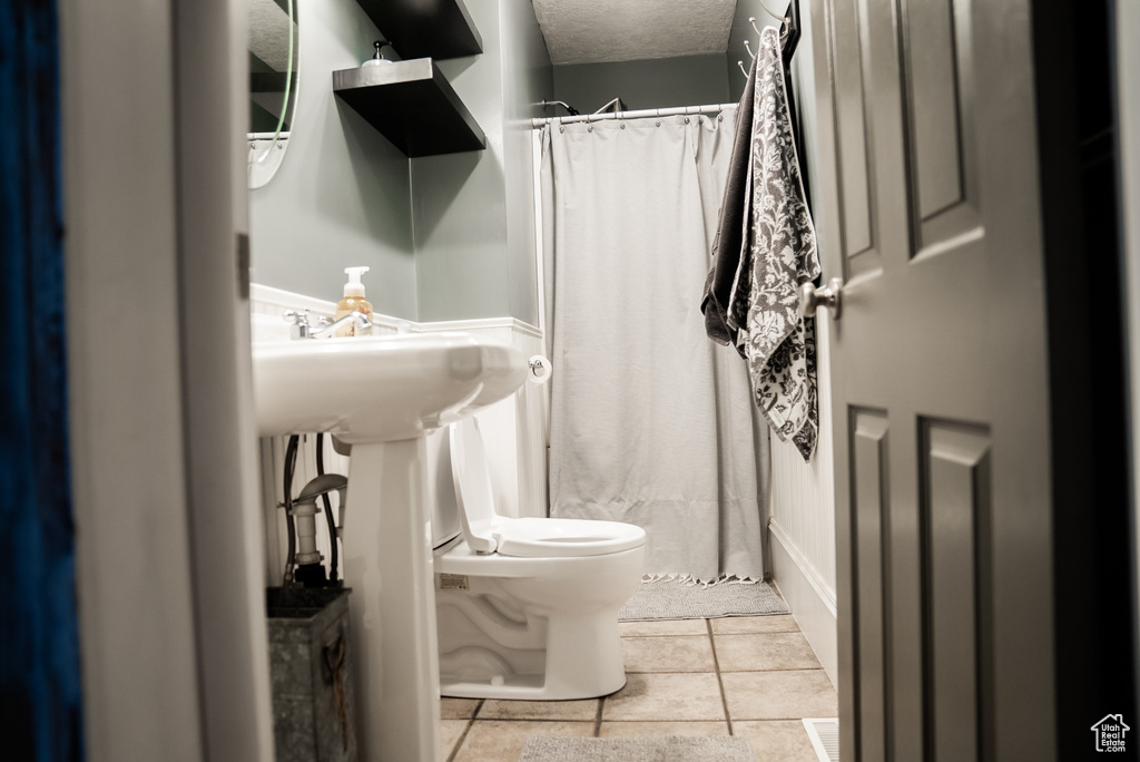 Bathroom with tile patterned floors, a textured ceiling, and toilet