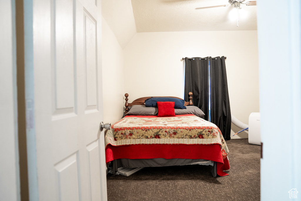 Carpeted bedroom featuring lofted ceiling and ceiling fan