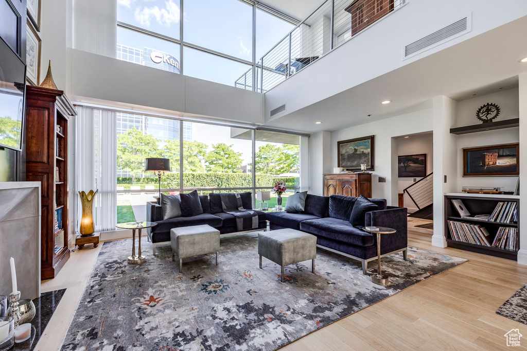 Living room with light hardwood / wood-style floors and a towering ceiling