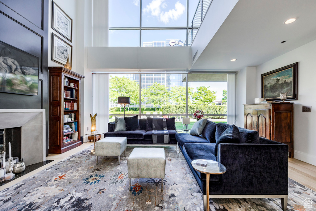 Living room with light hardwood / wood-style flooring, a high end fireplace, and a high ceiling