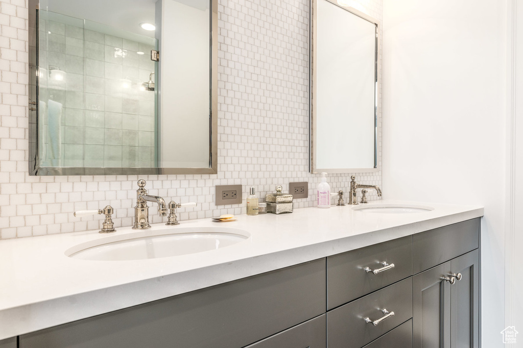 Bathroom with decorative backsplash, tile walls, and dual vanity