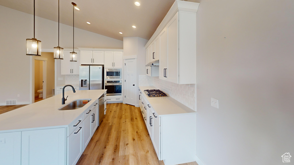 Kitchen featuring stainless steel appliances, tasteful backsplash, a kitchen island with sink, and sink