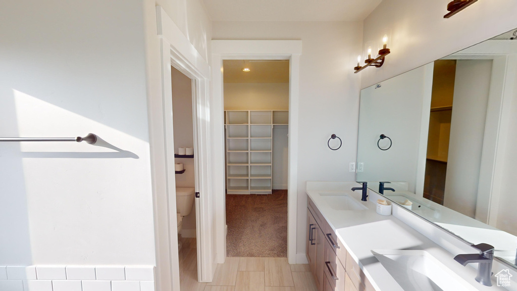 Bathroom featuring dual bowl vanity, tile flooring, and toilet