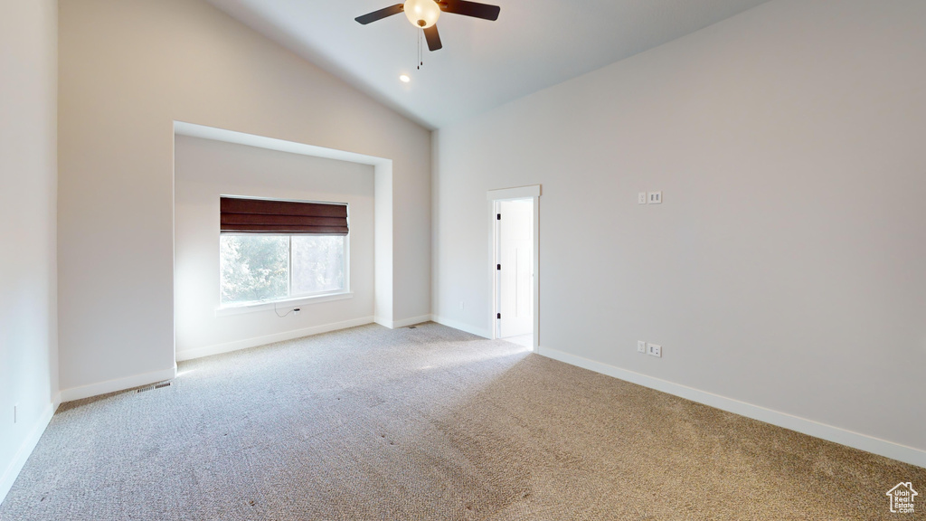 Carpeted empty room featuring high vaulted ceiling and ceiling fan