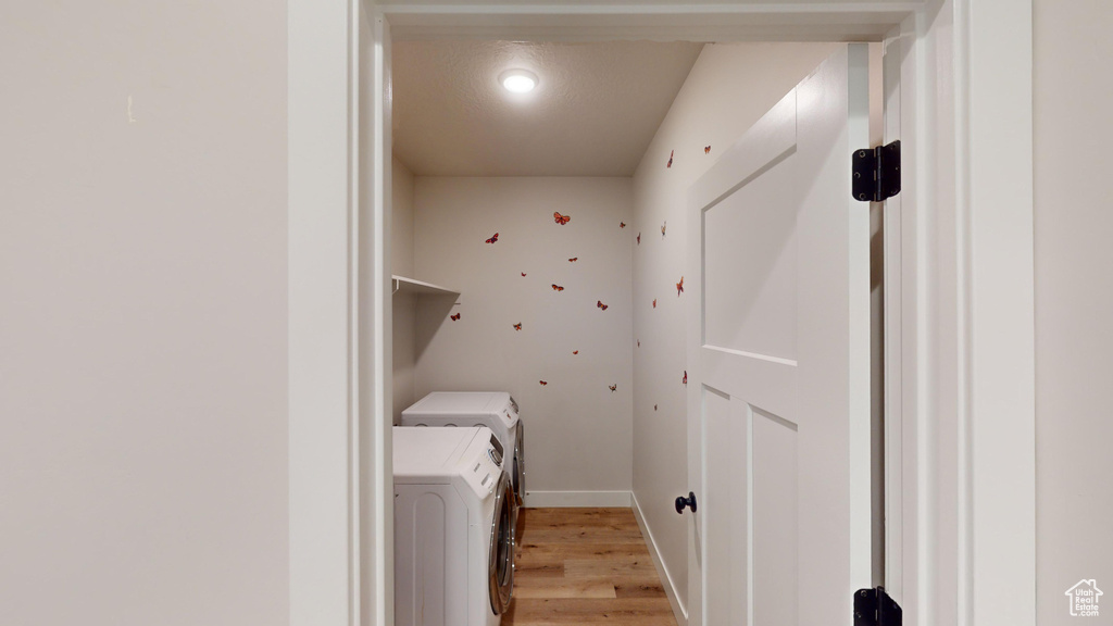 Laundry area with washer and clothes dryer and light wood-type flooring